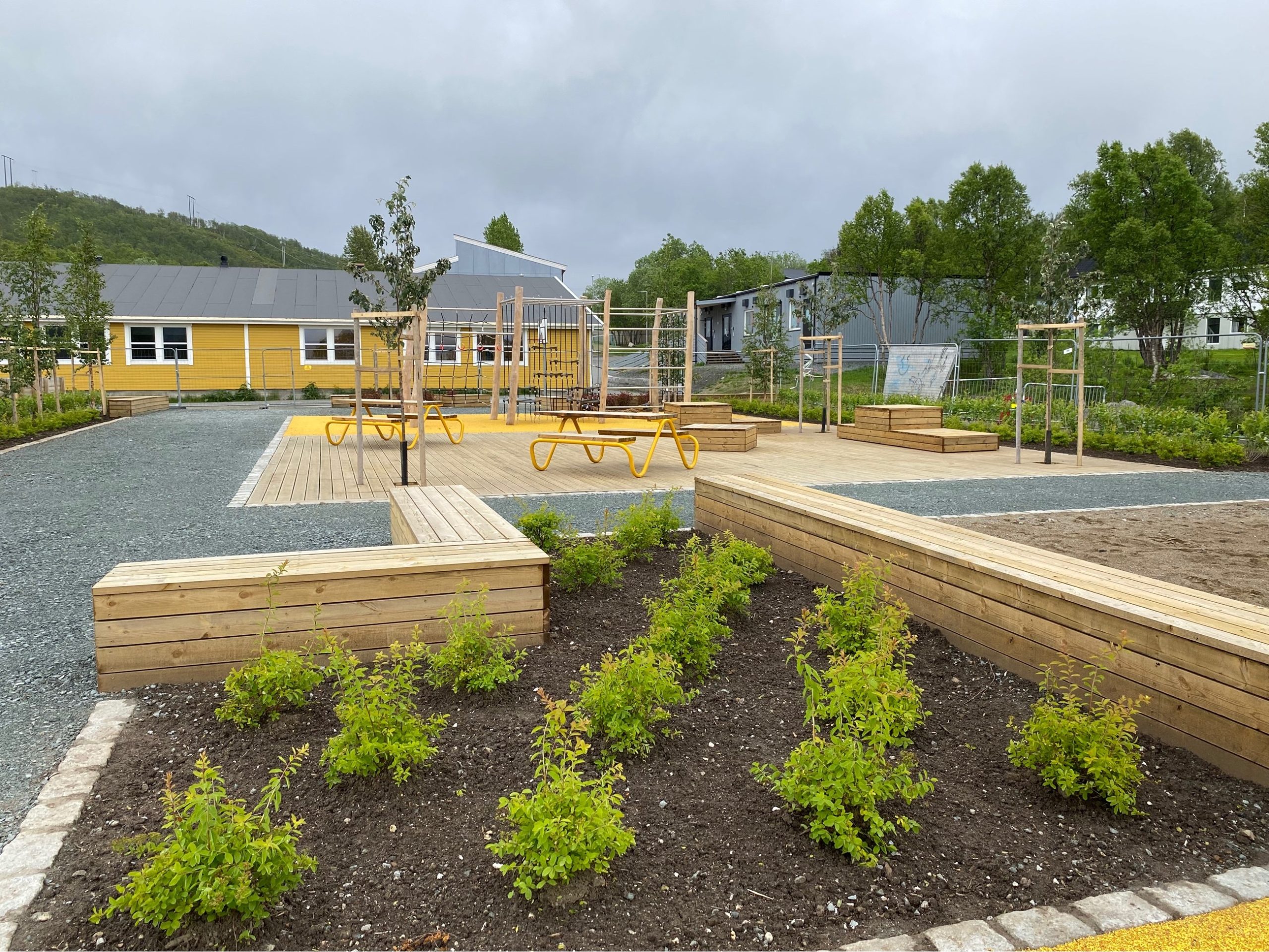a playground with a yellow building and trees