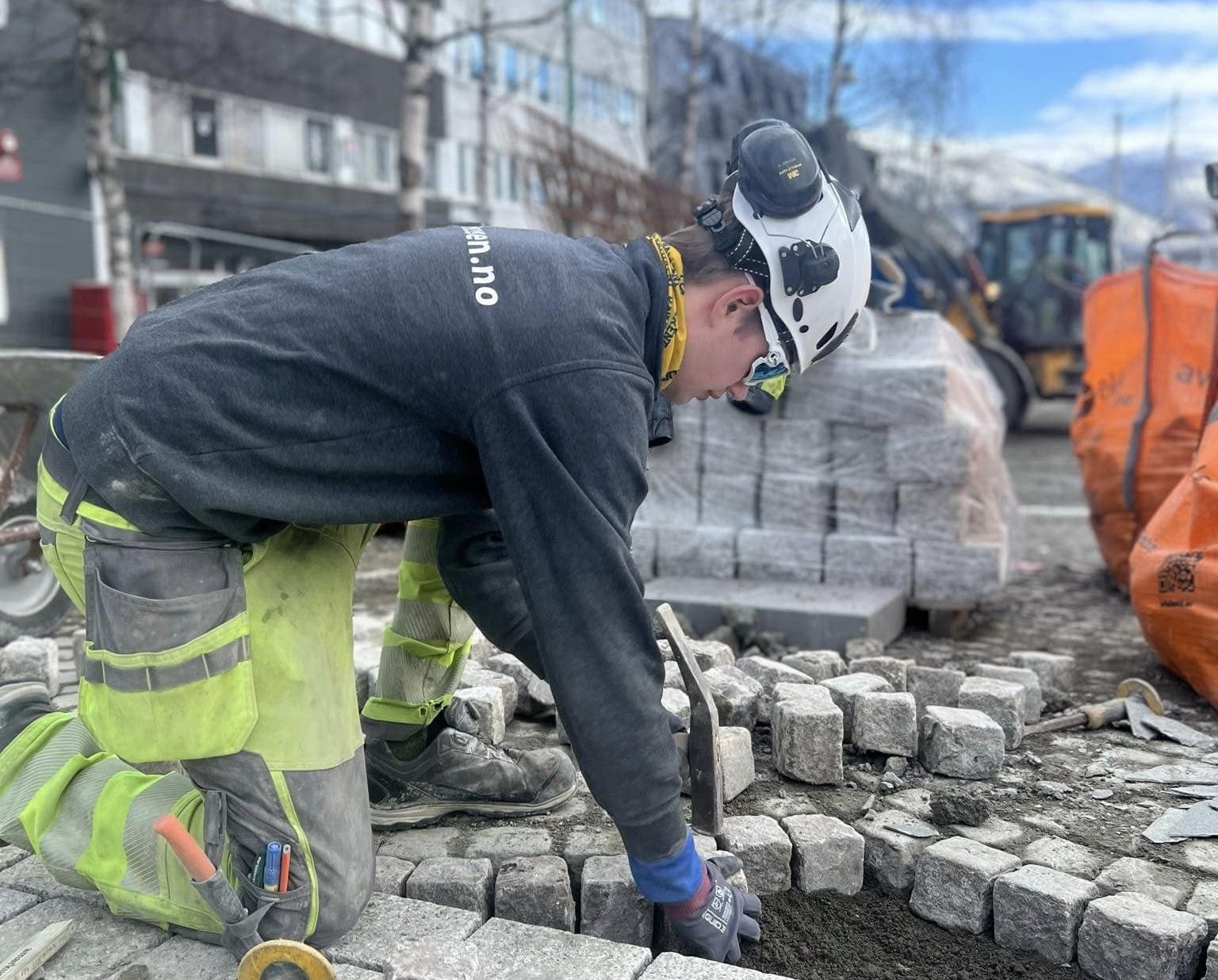 a man in a helmet and hardhat working on a sidewalk