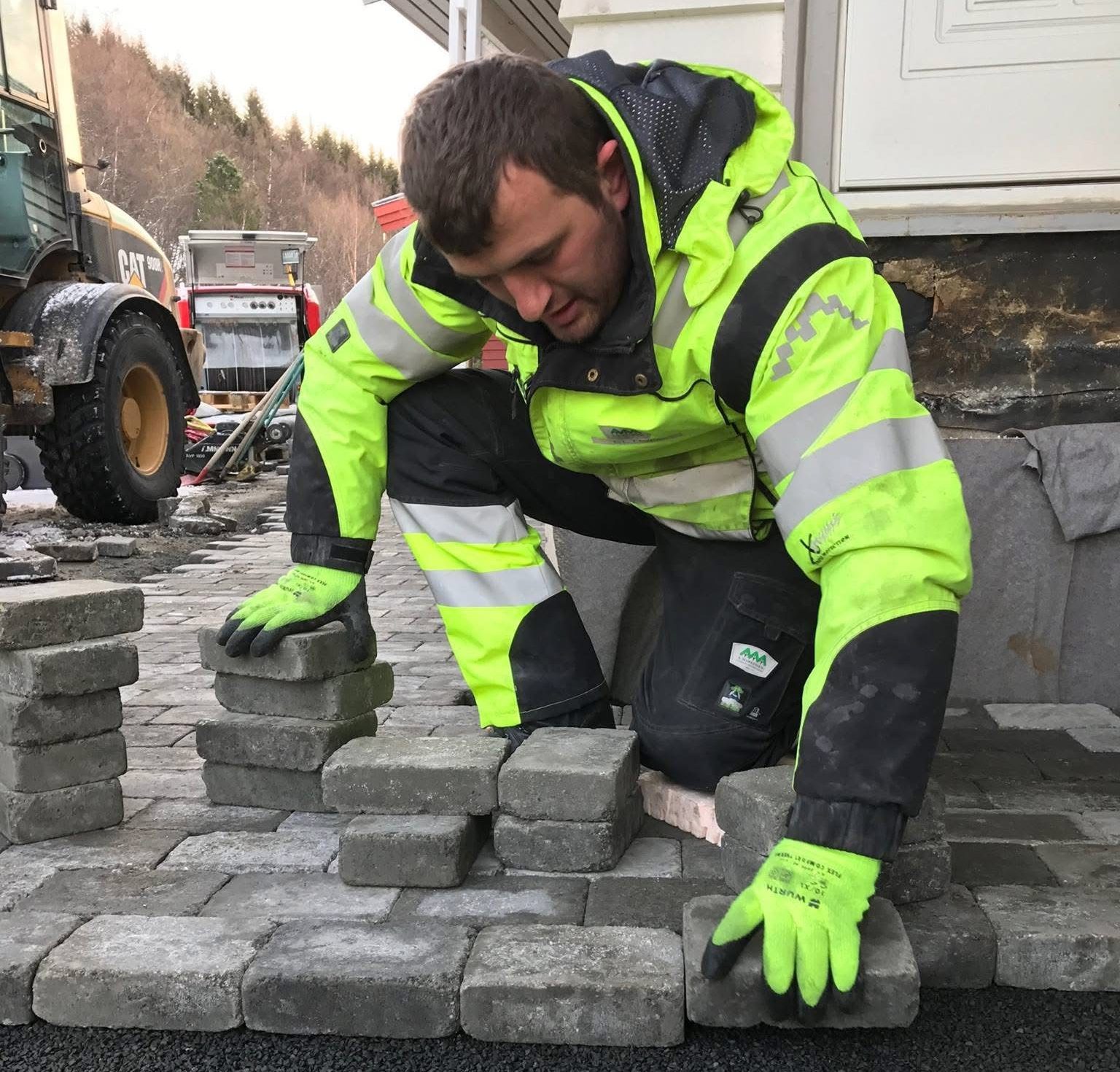 a man in a reflective jacket stacking bricks