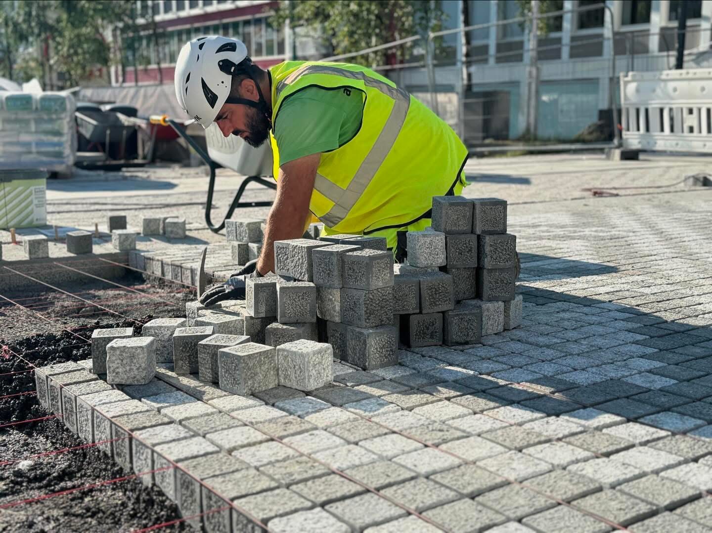 a man in a safety vest and helmet building a sidewalk